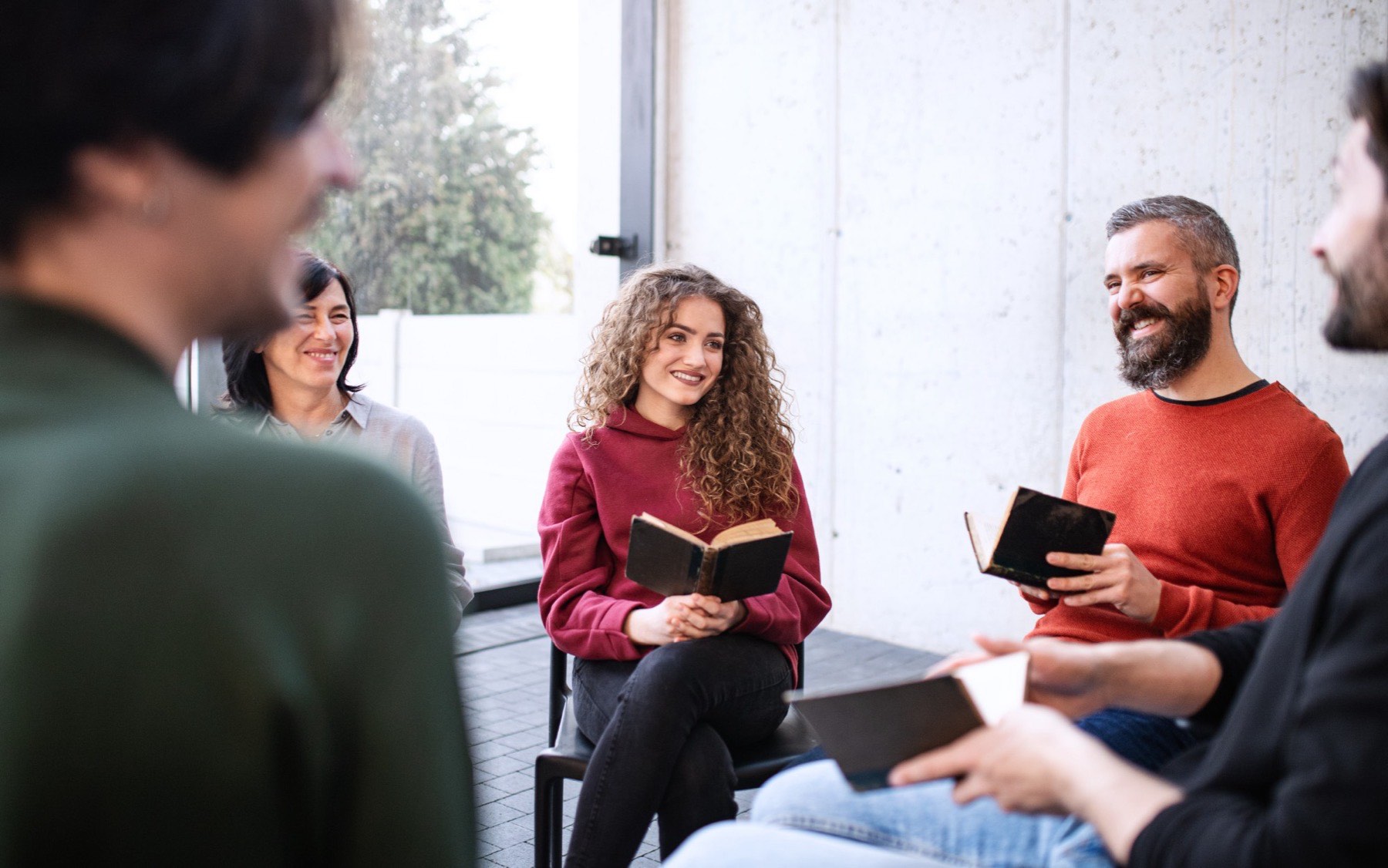 Grupo pequeno sentado em círculo, com Bíblias abertas, conversando e sorrindo